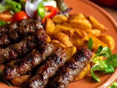 Traditional Bosnian ćevapi served with onions, ajvar and French fries